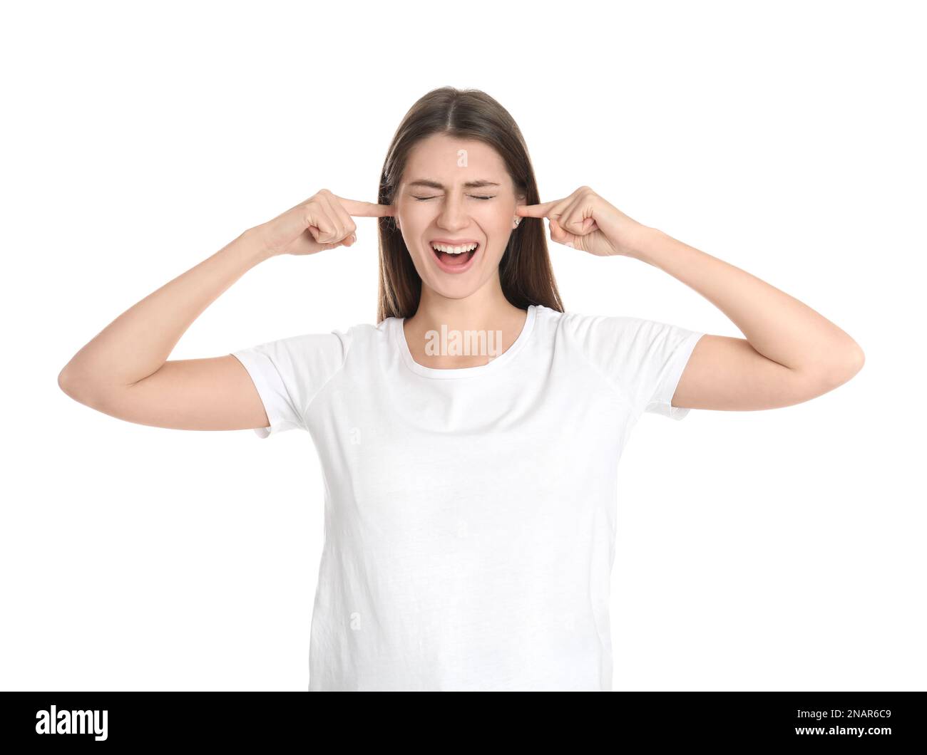 Emotionale junge Frau, die ihre Ohren mit Fingern auf weißem Hintergrund bedeckt Stockfoto