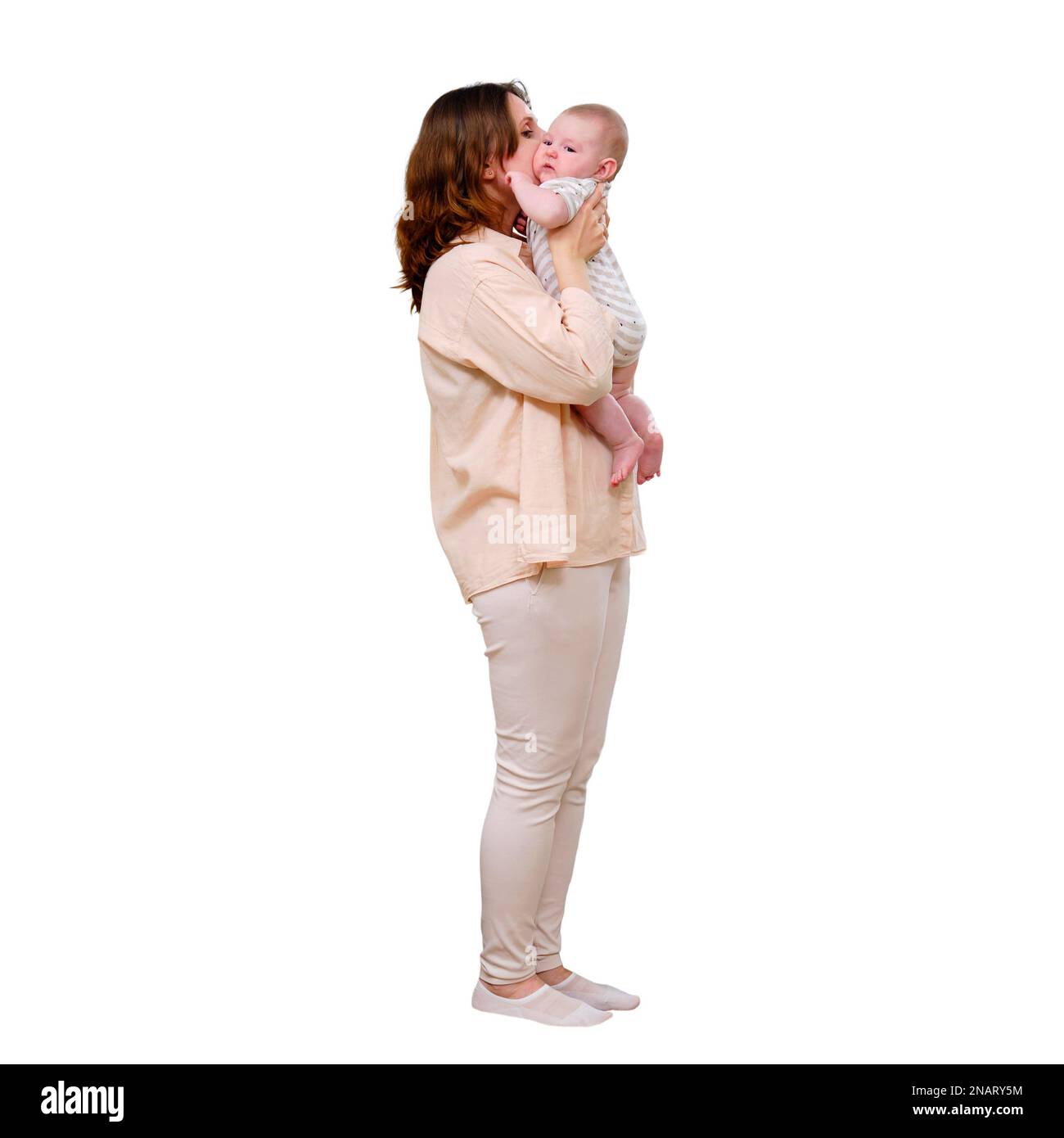 Erwachsene Frau, die das Kind mit dem Baby in einem Wohnzimmer in der Nähe des Herbstfensters küsst, isoliert auf weißem Hintergrund Stockfoto