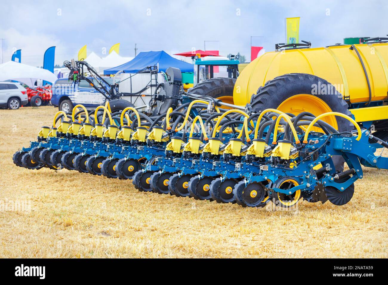 Eine mehrreihige Sämaschine mit pneumatischem Mechanismus auf dem Hintergrund eines landwirtschaftlichen Feldes an einem sonnigen Tag. Stockfoto