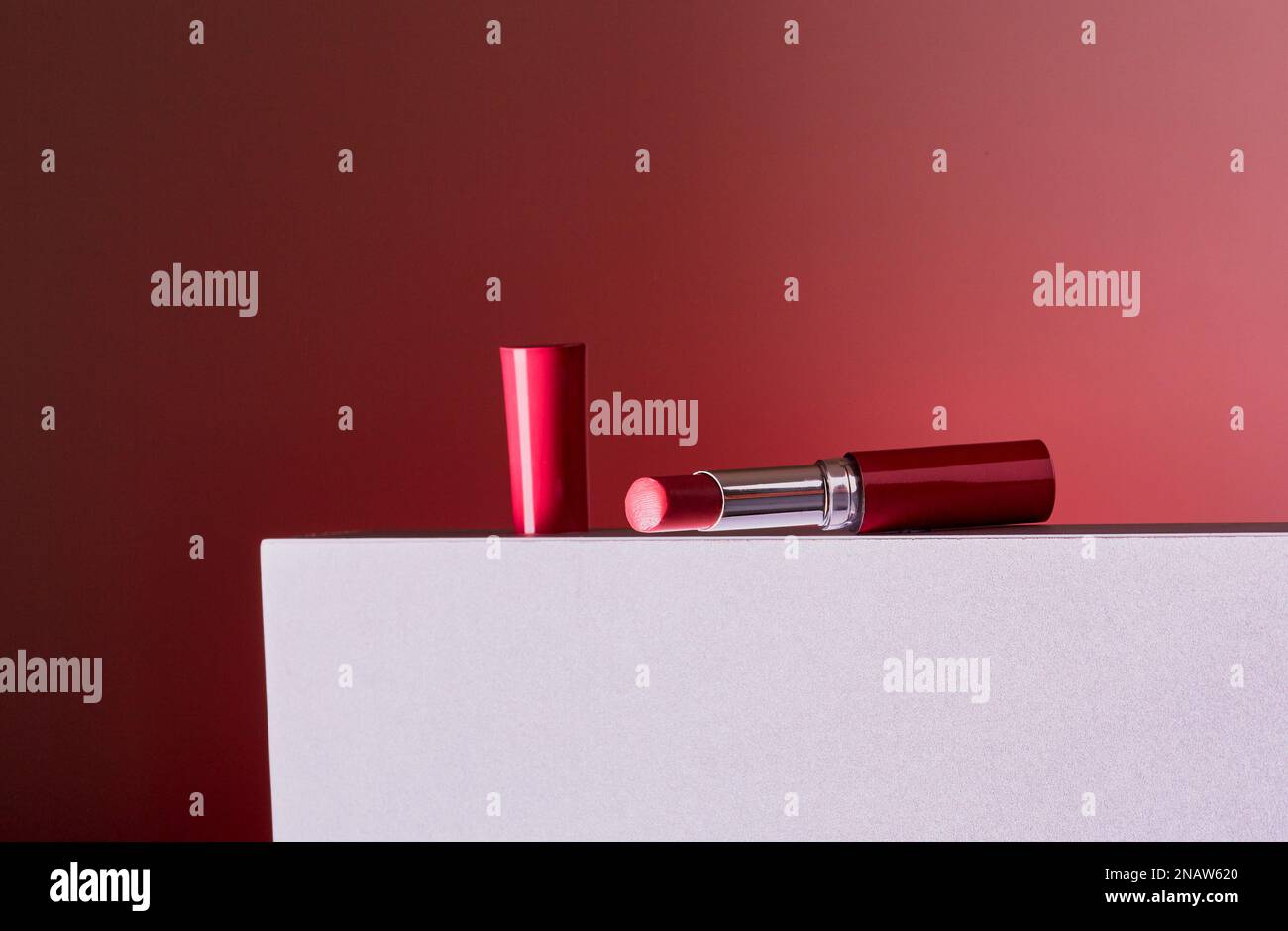 Roter Lippenstift isoliert auf einem Block mit rotem Verlaufshintergrund. Stockfoto