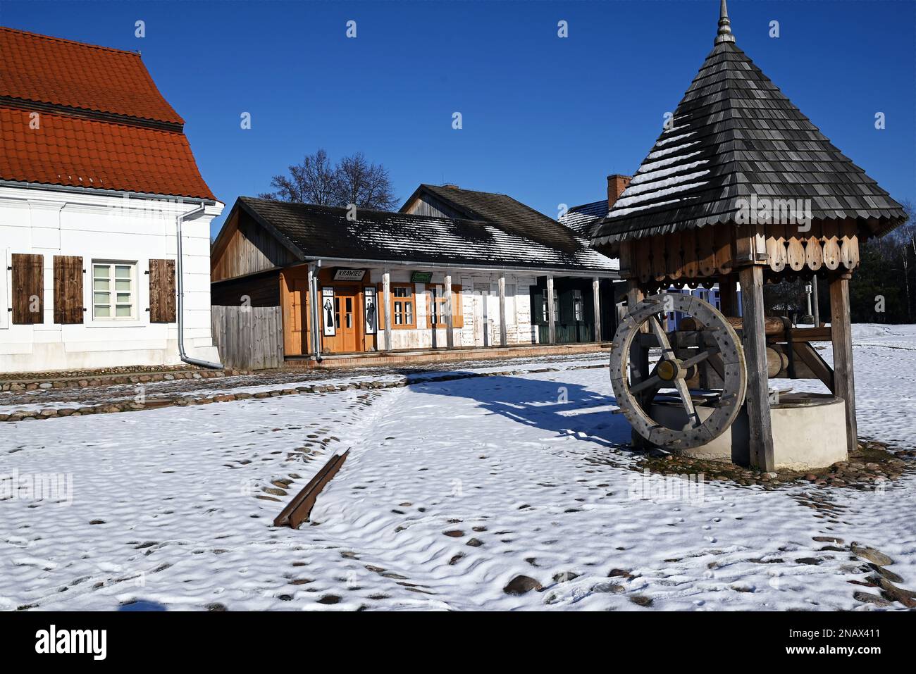 Alte Geschäfte und historische Brunnen auf dem Marktplatz in der polnischen Provinzstadt, wie im ethnologischen Museum in Lublin, Polen, zu sehen - verschneite Winterszene. Stockfoto