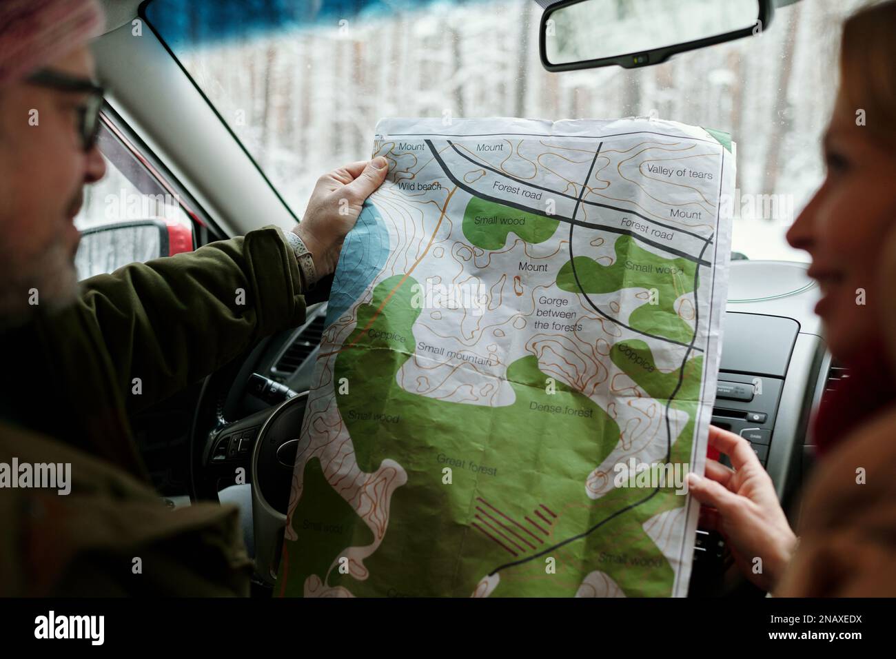 Konzentrieren Sie sich auf die lokale Karte in Papierform, die von einem erwachsenen Ehemann und einer Ehefrau im Auto aufbewahrt wird und die Beratung darüber bietet, wohin Sie gehen und welche Route Sie wählen sollten Stockfoto