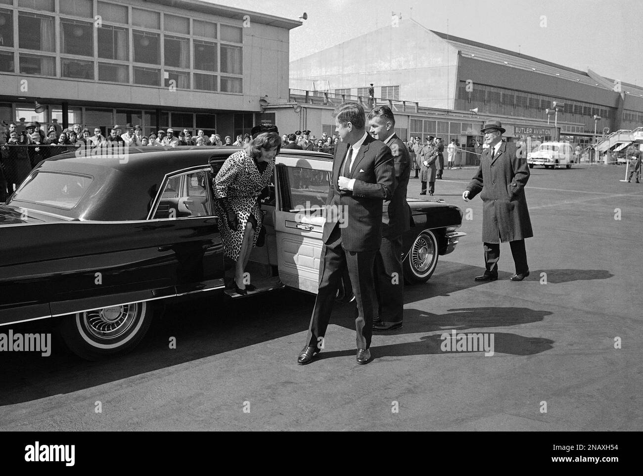 President John F. Kennedy holds open the door for his wife is they arrive at National Airport in Arlington, Va., on March 8, 1962, where the first lady boarded a plane for New York. Mrs. Jacqueline Kennedy, plans to stay overnight in New York and then will fly to Rome, Italy, to start a journey to India. The president boarded the plane with his wife and left after a stay of about three minutes. (AP Photo) Stockfoto