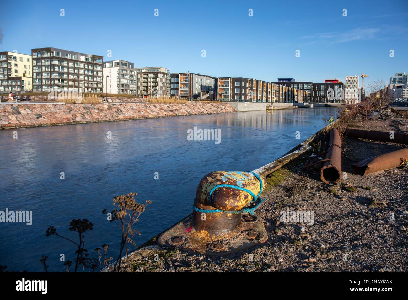 Alter Festmacher am Saukonlaituri-Dock mit neu gebauten Wohngebäuden im Hintergrund im Bezirk Länsisatama in Helsinki, Finnland Stockfoto