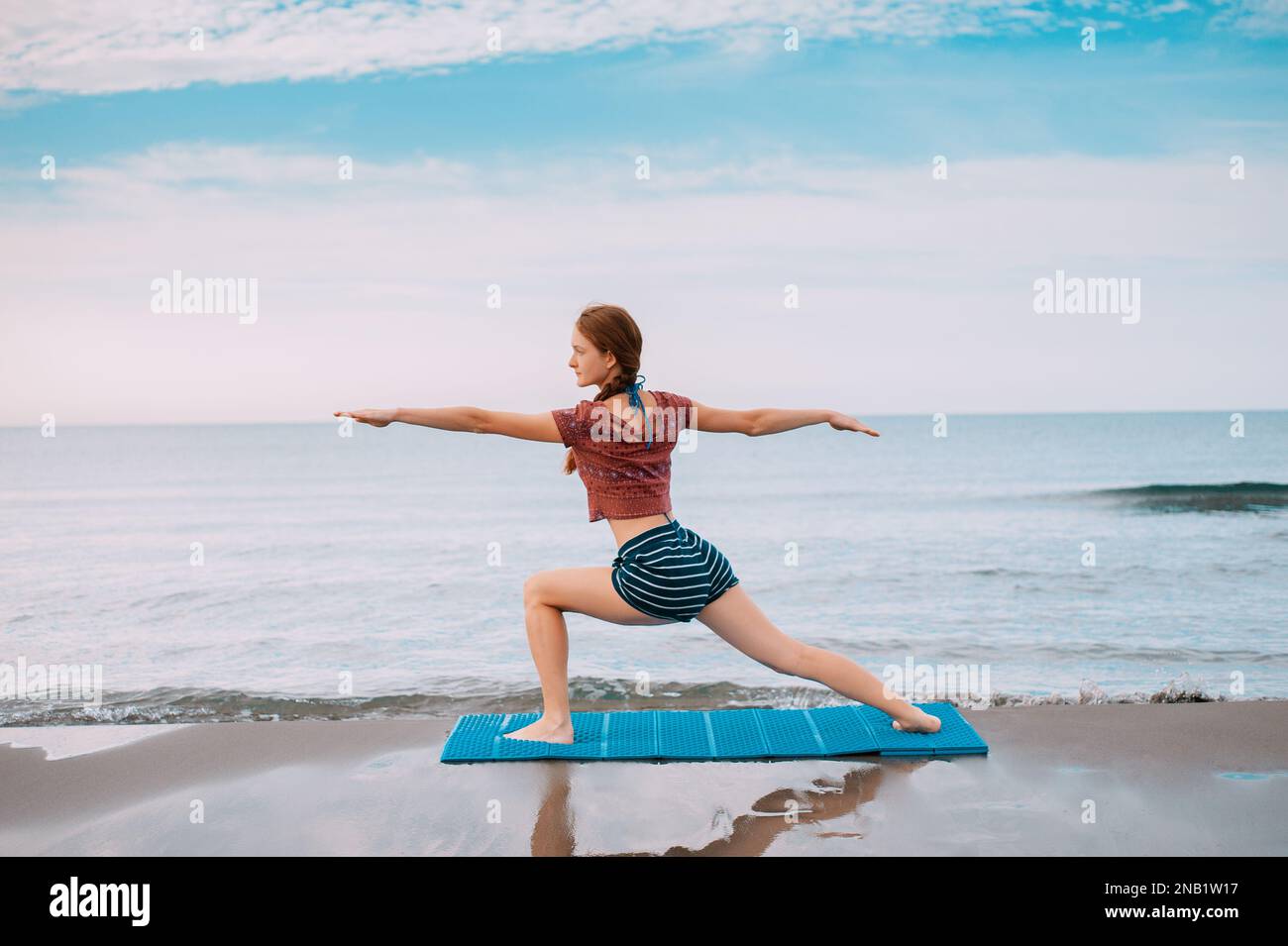 Active Sport Rothaarige, die am Strand Yoga macht in Montenegro Side View, Female ist in Sportkleidung am Strand der Adria Stockfoto