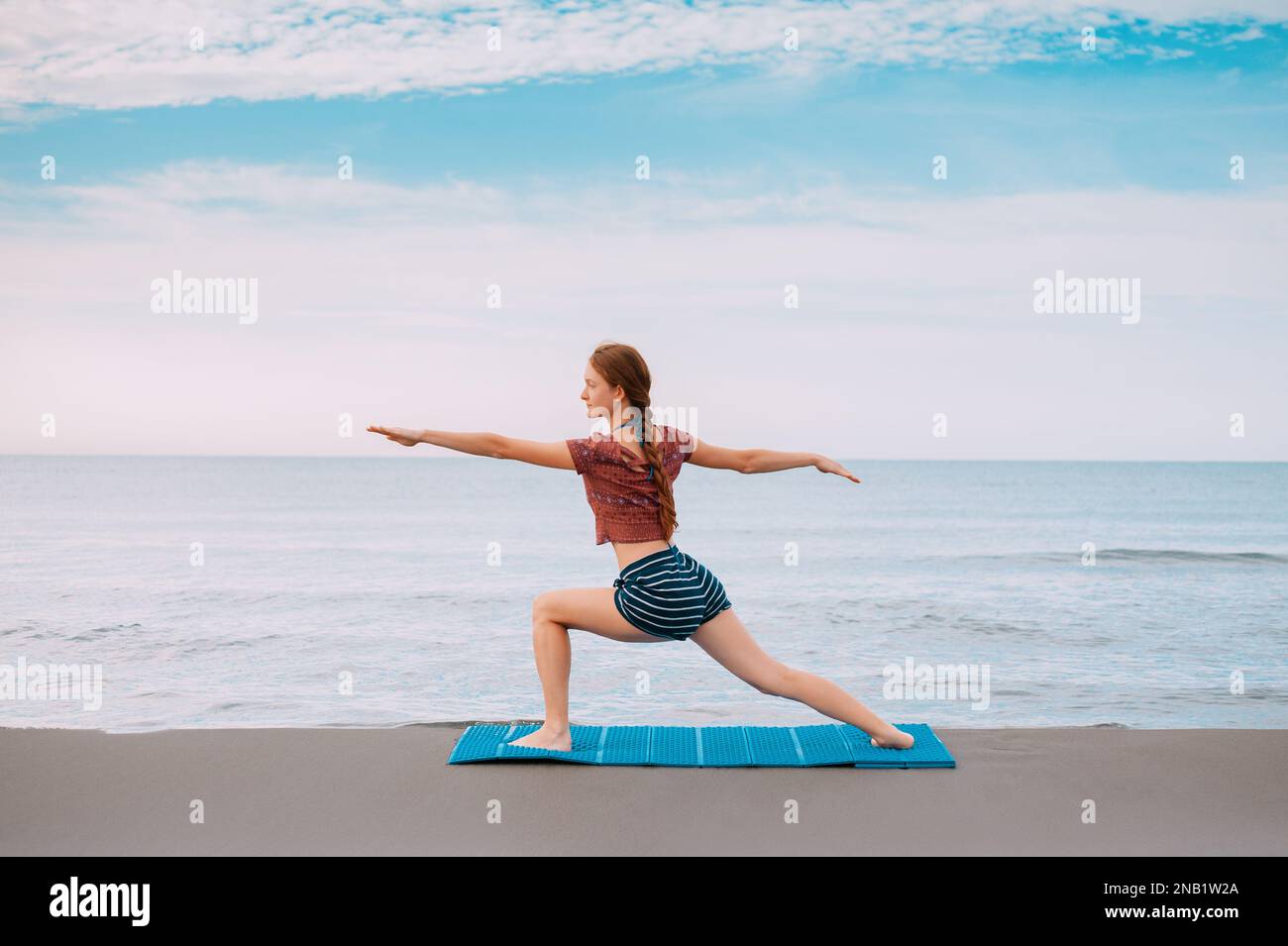 Active Sport Rothaarige, die am Strand Yoga macht in Montenegro Side View, Female ist in Sportkleidung am Strand der Adria Stockfoto