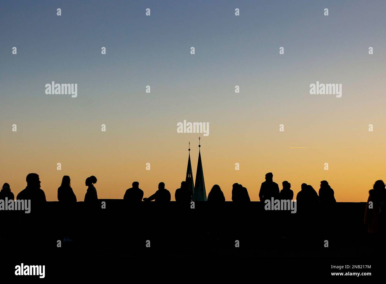 Nürnberg, Deutschland. 13. Februar 2023. Menschen stehen auf einer Aussichtsplattform des Kaiserburg Nürnberg bei Sonnenuntergang. Die Türme der Sebalduskirche sind dahinter zu sehen. Nürnberg, 13. Februar 2023. Kredit: dpa/Alamy Live News Stockfoto