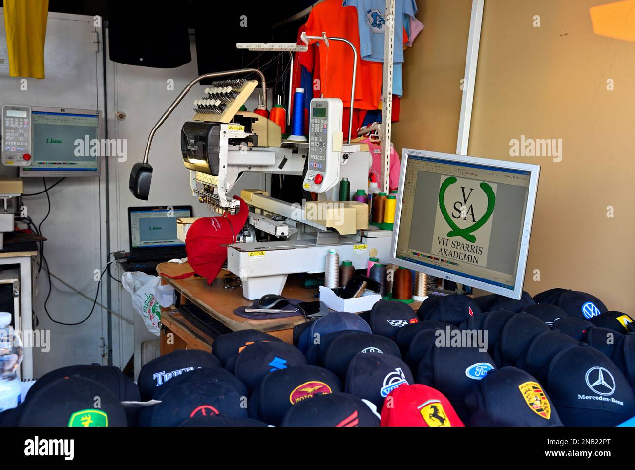 Mehrfarbige sechs-Kopf-Stickerei zwölf Nadeln gewerbliche Stickerei Maschine Logo auf Hut im Touristenzentrum von Maspalomas, Gran Canaria Stockfoto