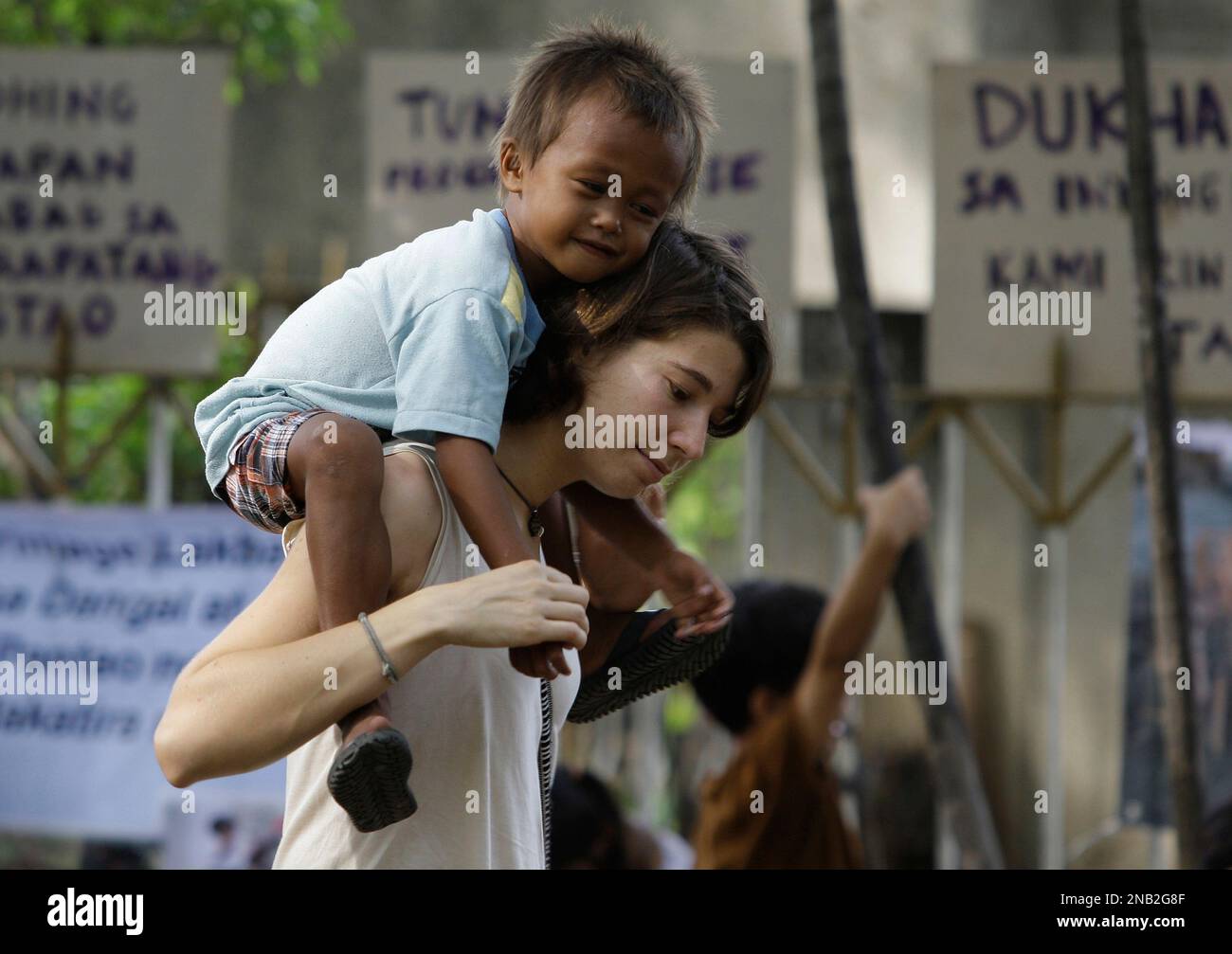 CAPTION CORRECTION, CORRECTS DATE - A foreign volunteer carries a Filipino street child as they attend an event in observance of international Day of Overcoming Extreme Poverty at the Rizal Park in Manila, Philippines on Sunday Oct. 16, 2011. The annual event also observed in other countries seeks to find ways of effectively easing poverty, which afflicts nearly a third of the Philippines' 94 million people. (AP Photo/Aaron Favila) Stockfoto