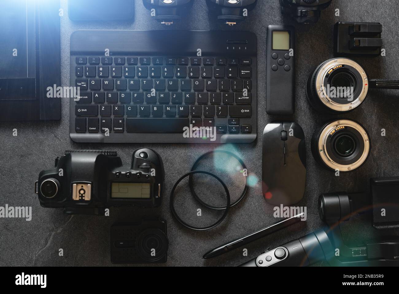 Digitale Foto-Workstation mit schwarzem Hintergrund. Draufsicht von Digitalkamera, Blitz, Objektiv und Laptop. Professionelle Fotoausrüstung. Stockfoto