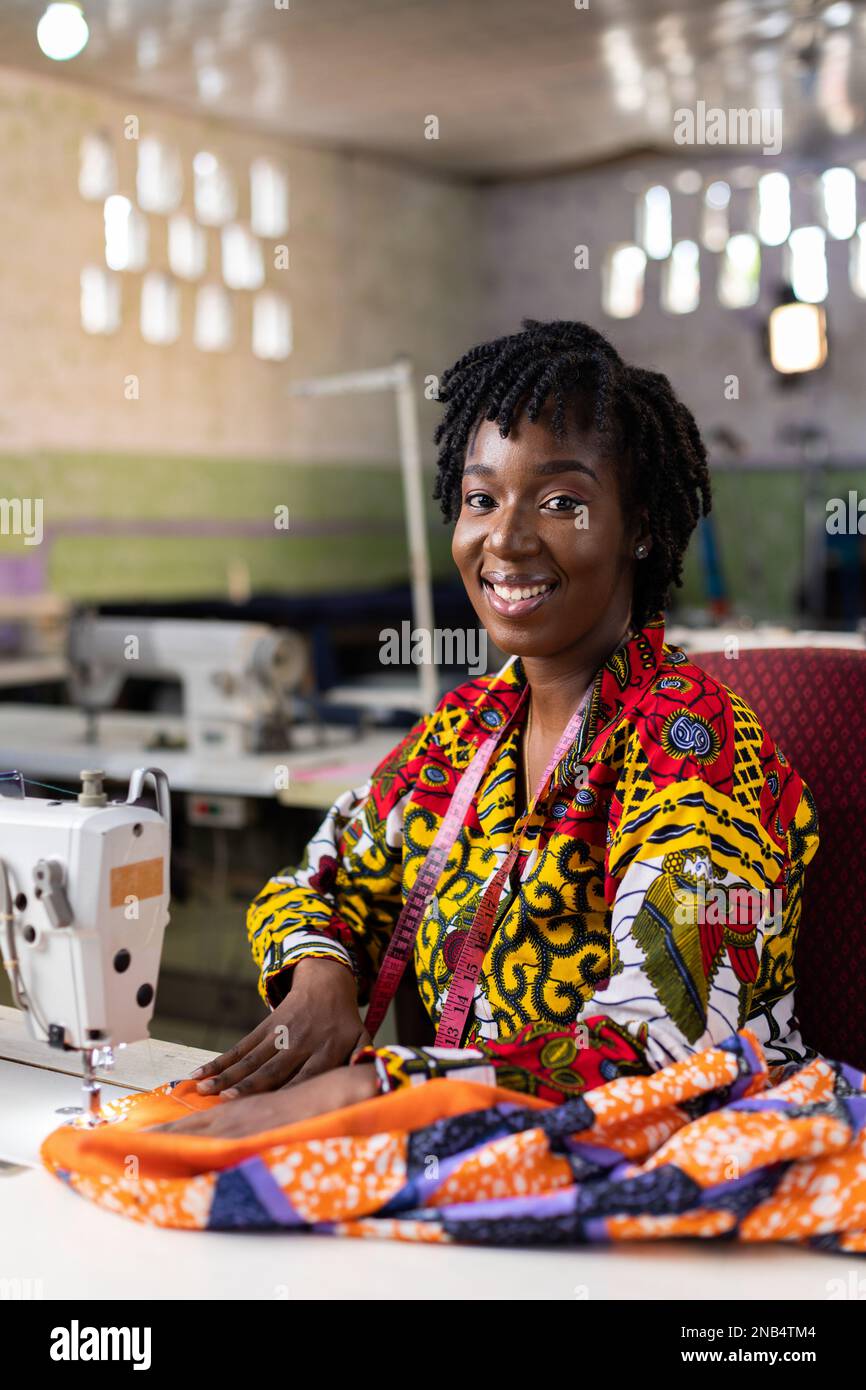 Afrikanische Schneiderin mit haaren von locs, die in ihrem Modedesignstudio arbeitet. Stockfoto