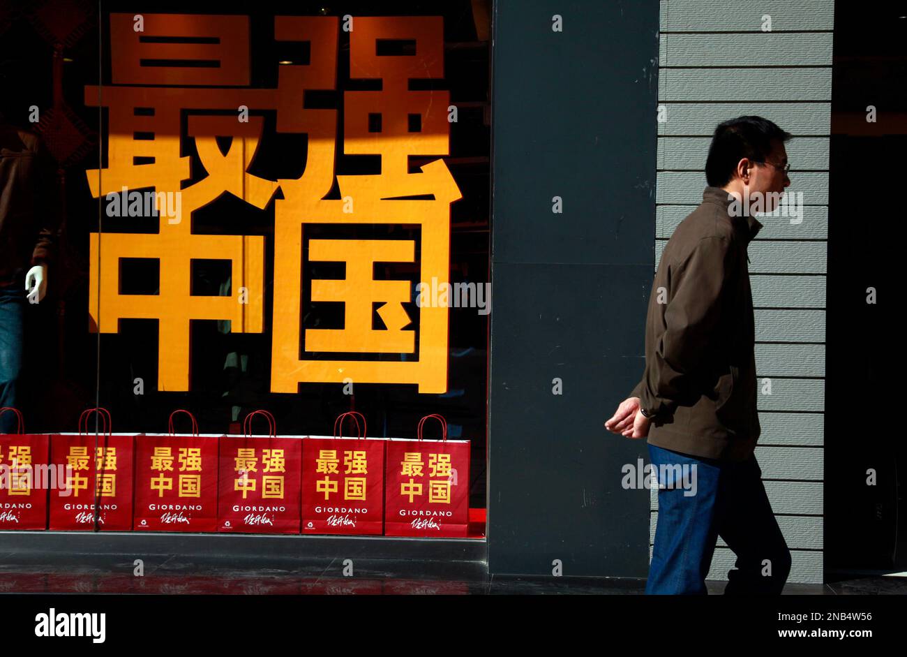 A Chinese man walks past a clothing store using the slogan "The Strongest, China" to promote its apparels during the National Day celebrations in Beijing, China, Sunday, Oct. 2, 2011. (AP Photo/Ng Han Guan) Stockfoto