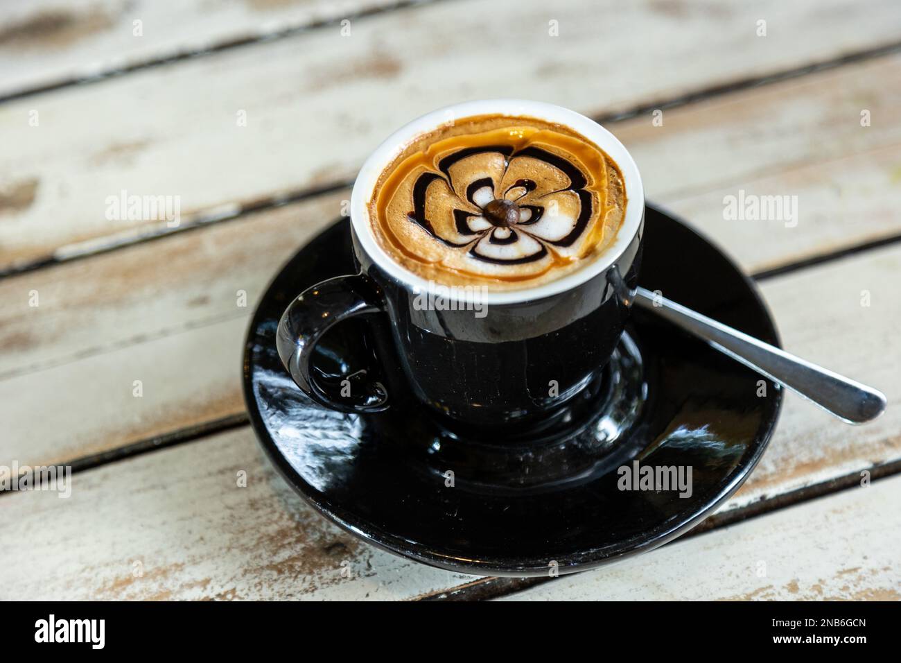 Eine Nahaufnahme einer Blumenzeichnung auf dem Cappuccino-Schaum Stockfoto