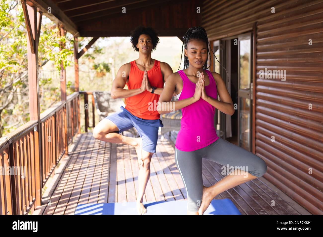 Glückliches afroamerikanisches Paar, das Zeit in einer Blockhütte verbringt und Yoga praktiziert. Blockhütte, Natur- und Lifestyle-Konzept. Stockfoto
