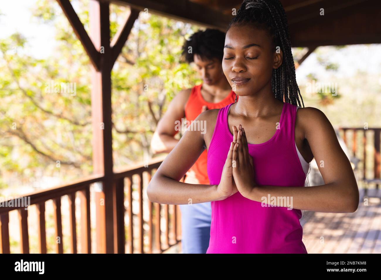 Glückliches afroamerikanisches Paar, das Zeit in einer Blockhütte verbringt und Yoga praktiziert. Blockhütte, Natur- und Lifestyle-Konzept. Stockfoto