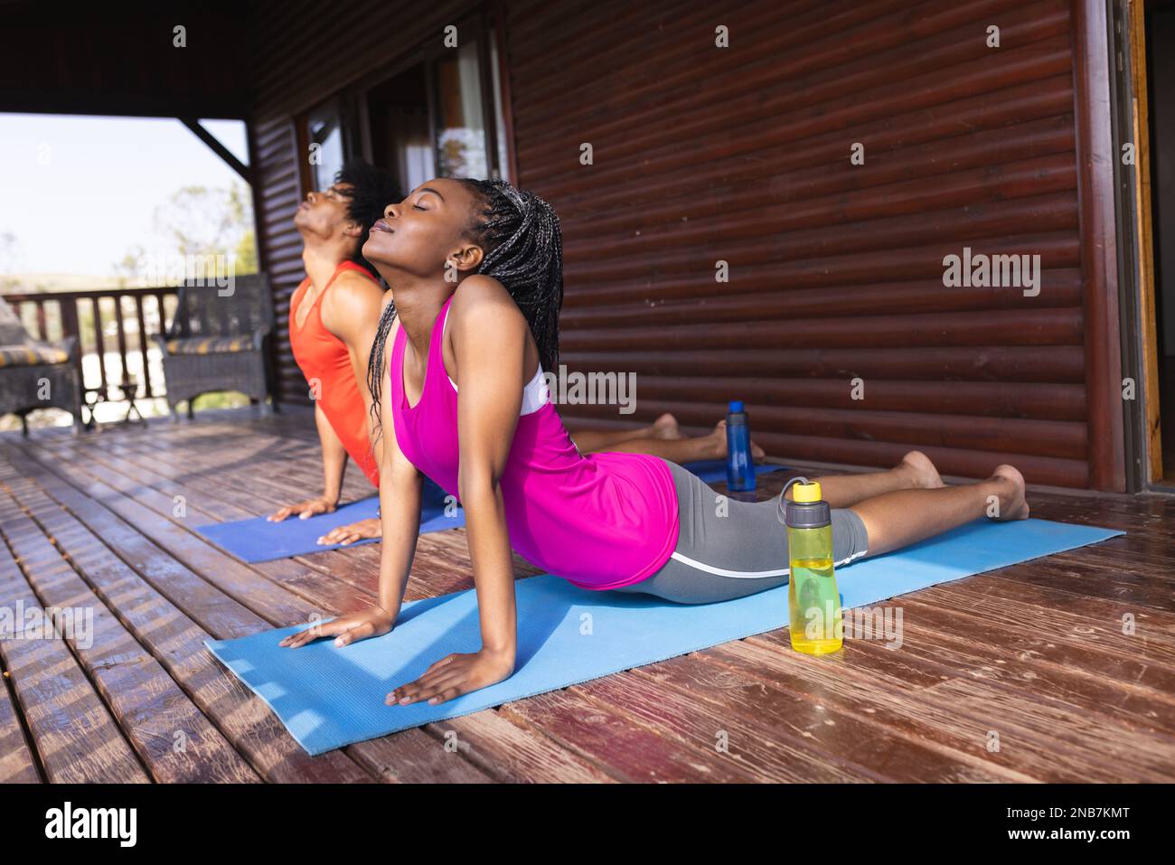 Ein afroamerikanisches Paar, das in einer Blockhütte Yoga auf Yoga-Matten praktiziert. Blockhütte, Natur- und Lifestyle-Konzept. Stockfoto