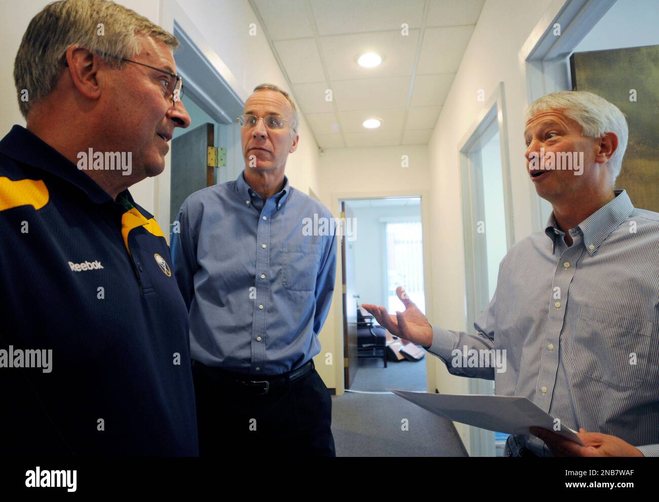 Buffalo Sabres NHL hockey owner Terry Pegula, left, makes a personalized delivery to season ticket holders Peter Brady, center, and Alan Schaefer at their office, in Amherst, N.Y, Wednesday, Sept. 14, 2011. Under new owner Pegula, the Sabres took a page out the Penguins' marketing game plan by having their team drive around town as glorified ticket couriers. (AP Photo/Doug Benz) Stockfoto