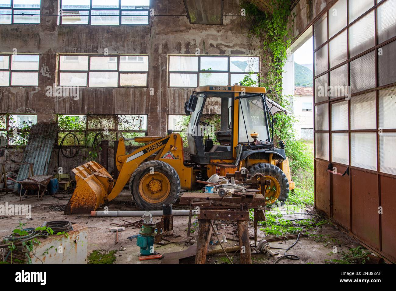 Ein Bagger, der von der Natur in einer alten Reparaturwerkstatt eingetaucht ist Stockfoto