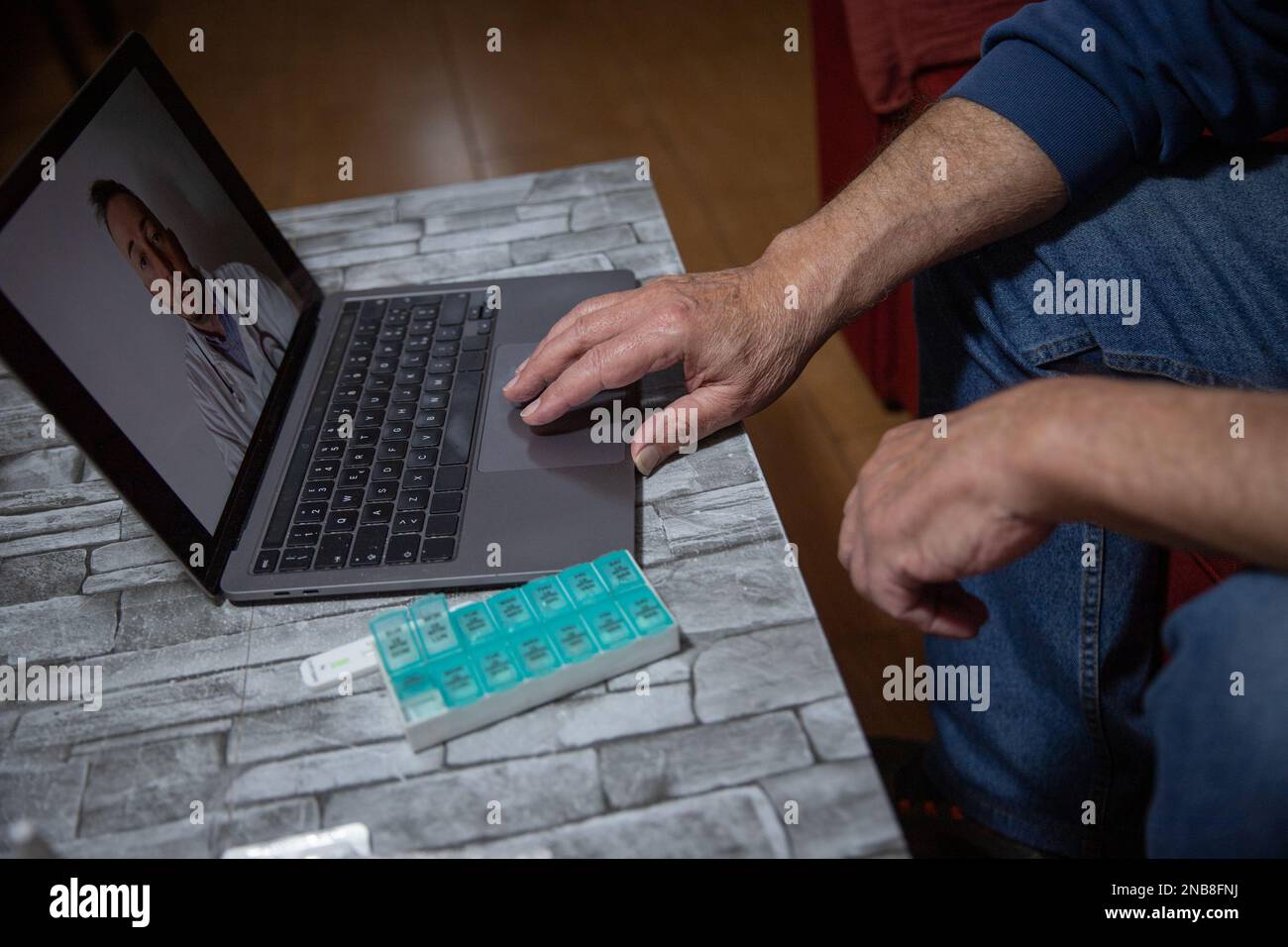 Hand eines älteren Mannes während einer Videokonferenz mit seinem Hausarzt, Telehealth-Konzept. Stockfoto