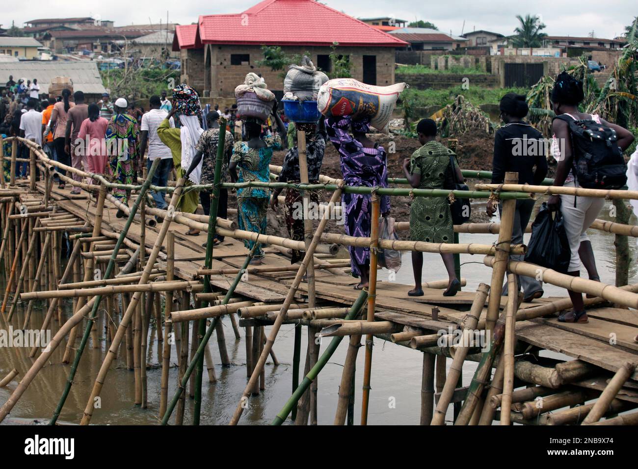 Residents walk across a makeshift bamboo bridge following a heavy down pour last week in Ibadan, Nigeria , Friday, Sept 2, 2011. Flash flooding across Nigeria's southwest killed at least 102 people in the last week, the country's Red Cross said .Some 1,500 people remain displaced by the torrential downpours, officials said.The major flood hit hardest in Oyo state's capital of Ibadan. Heavy rains there on Friday made a local dam overflow, sending water crashing through the informal settlements surrounding the city. The water also damaged three bridges in the area, trapping people in their neigh Stockfoto