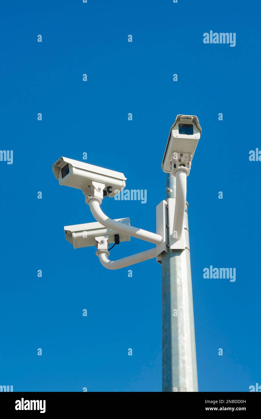 Drei Überwachungskameras auf einem Stab vor einem klaren blauen Himmel Stockfoto