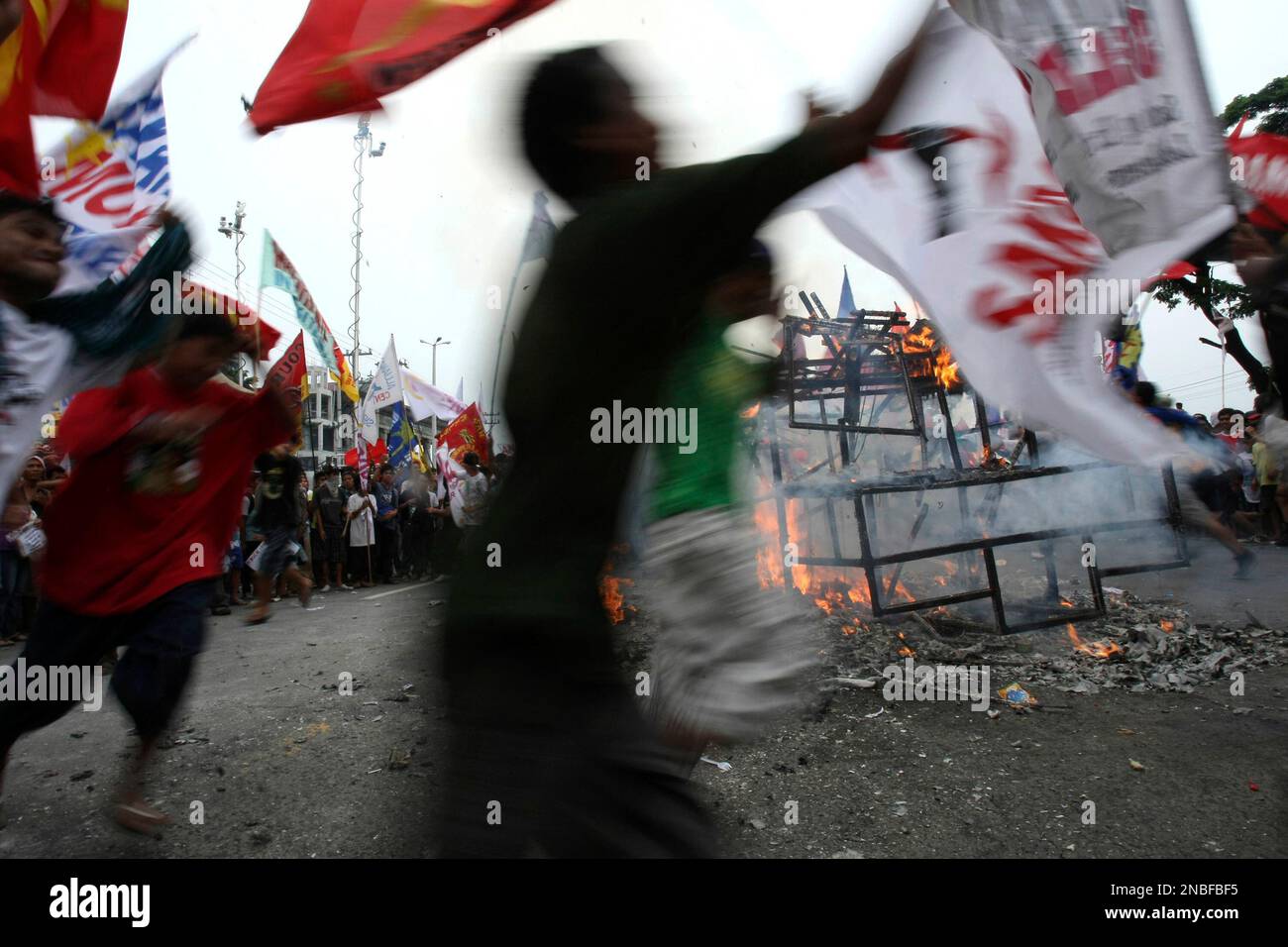 Protesters dance around a burning effigy of Philippine President Benigno Aquino III to protest his second State of the Nation Address at suburban Quezon city northeast of Manila, Philippines, Monday July 25, 2011. Thousands of mostly left-wing protesters marched in the capital to demand higher wages, farmland and the prosecution of the President's predecessor for alleged graft. (AP Photo/Bullit Marquez) Stockfoto