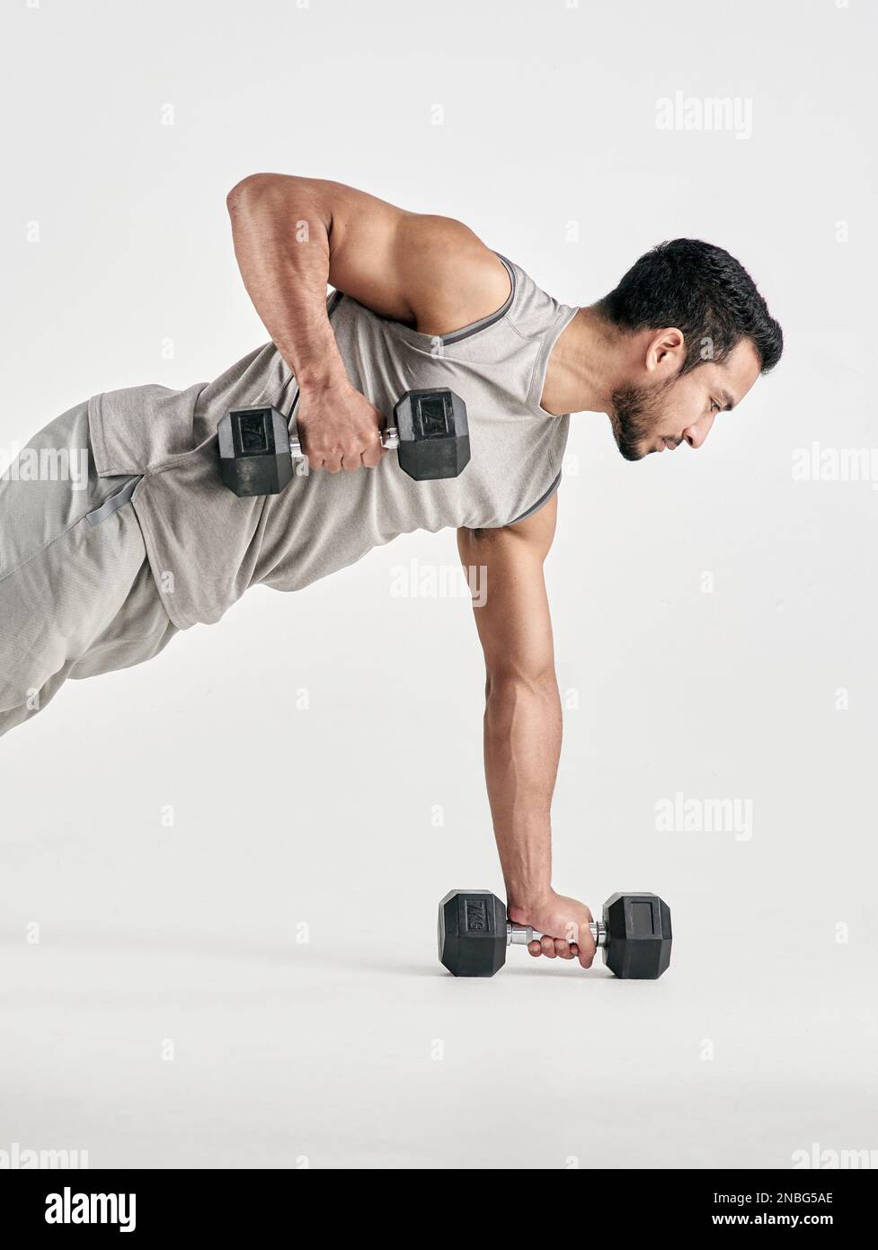 Gehen Sie über Ihre Grenzen hinaus. Studioaufnahme eines muskulösen jungen Mannes, der mit Kurzhanteln vor weißem Hintergrund trainiert. Stockfoto