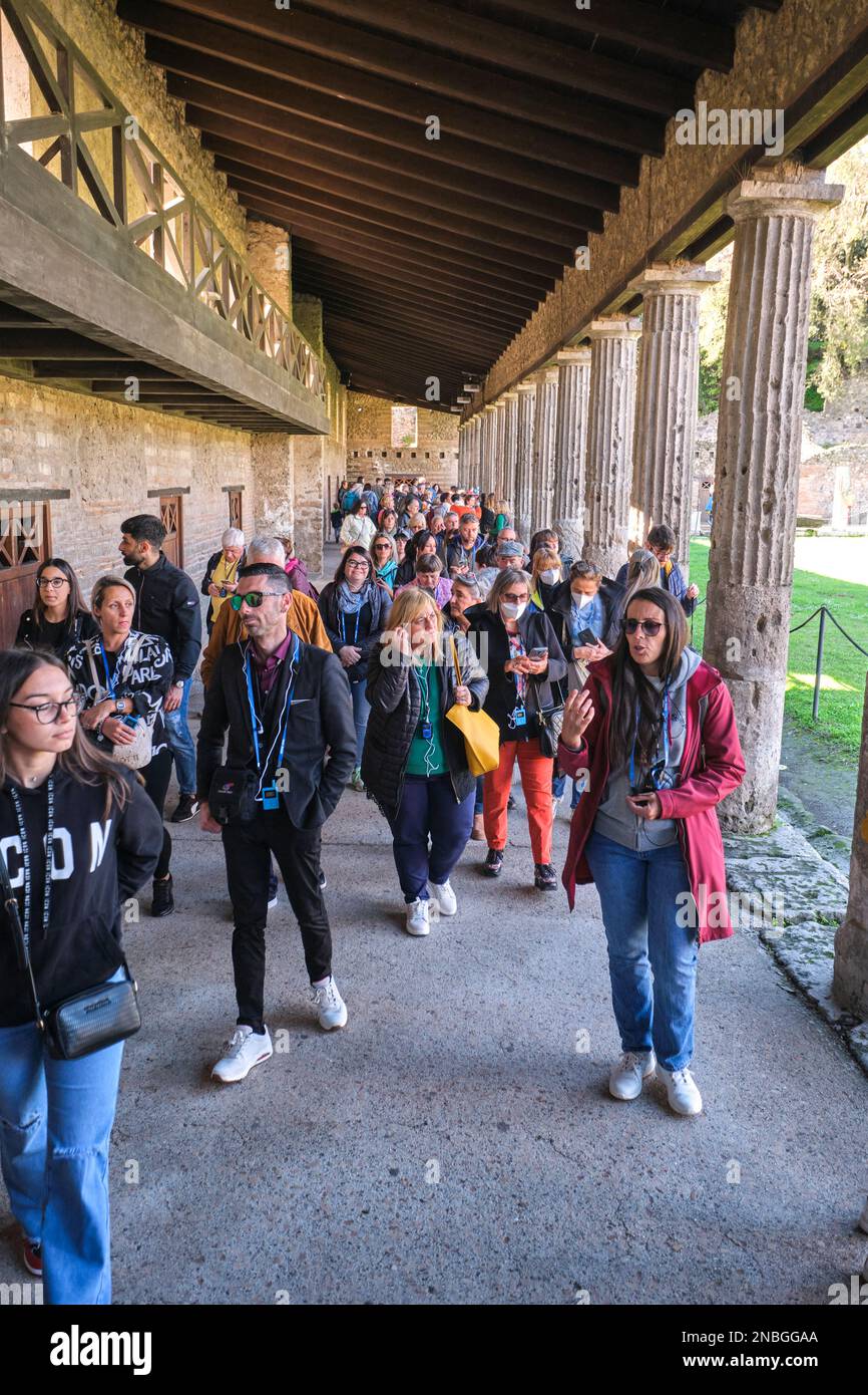 Gruppen von Touristen, Besucher packen, drängen sich in die Gegend um Quadriportico dei Teevi. Im Archäologischen Park von Pompeji in der Nähe von Neapel, Italien. Stockfoto