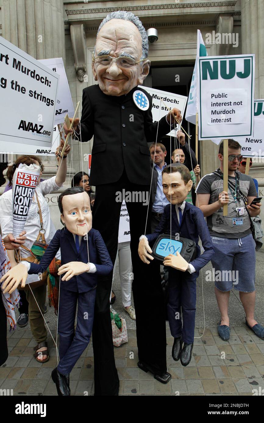 A protester amongst others dressed up as News Corp's chairman Rupert Murdoch holds puppets depicting British Prime Minister David Cameron, left, and Culture Secretary Jeremy Hunt, demonstrates outside the Department of Culture, Media and Sport in London against the government announcement Thursday approving takeover of BSkyB by Rupert Murdoch's News Corporation , Thursday, June 30, 2011. (AP Photo/Sang Tan) Stockfoto
