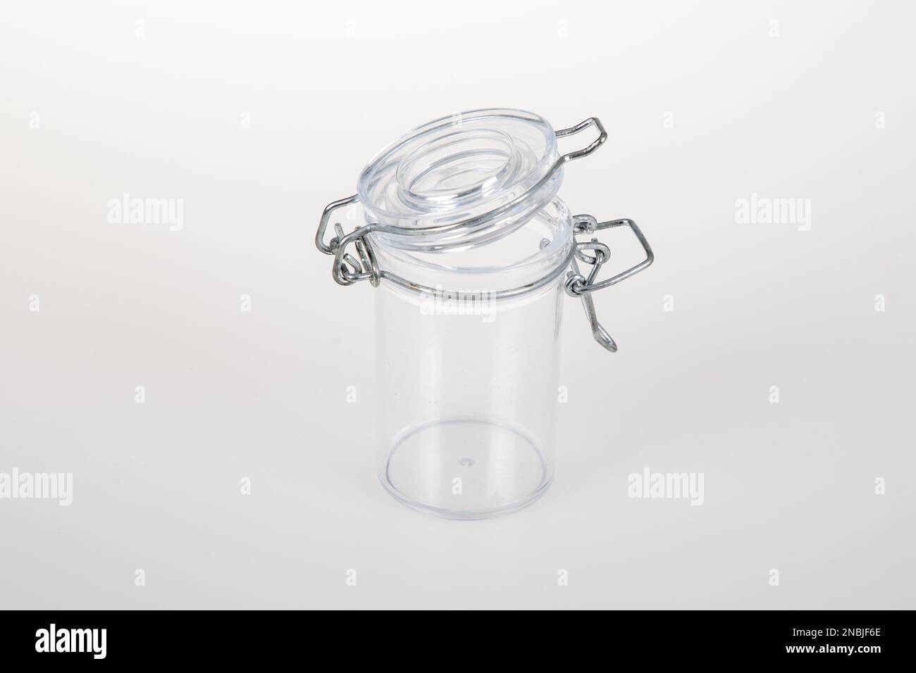 Öffnen Sie den Glasbehälter mit einer Metallklemme auf weißem Hintergrund Stockfoto