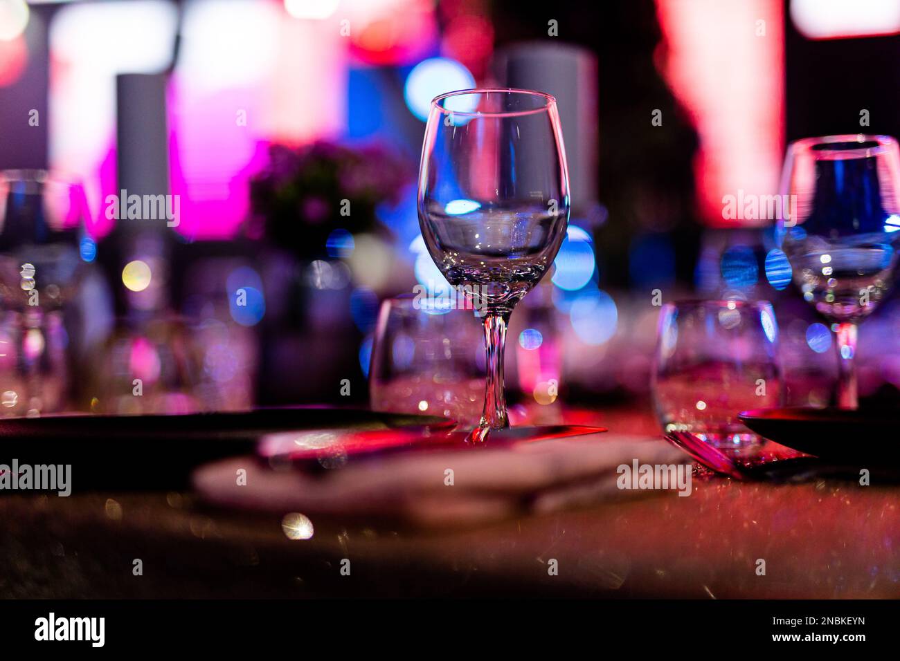 Luxuriöse Tischgedecke für feines Essen mit und Gläsern, Gießen von Wein ins Glas. Schöner unscharfer Hintergrund. Vorbereitung auf die Feiertagshochzeit. Extravagant Stockfoto