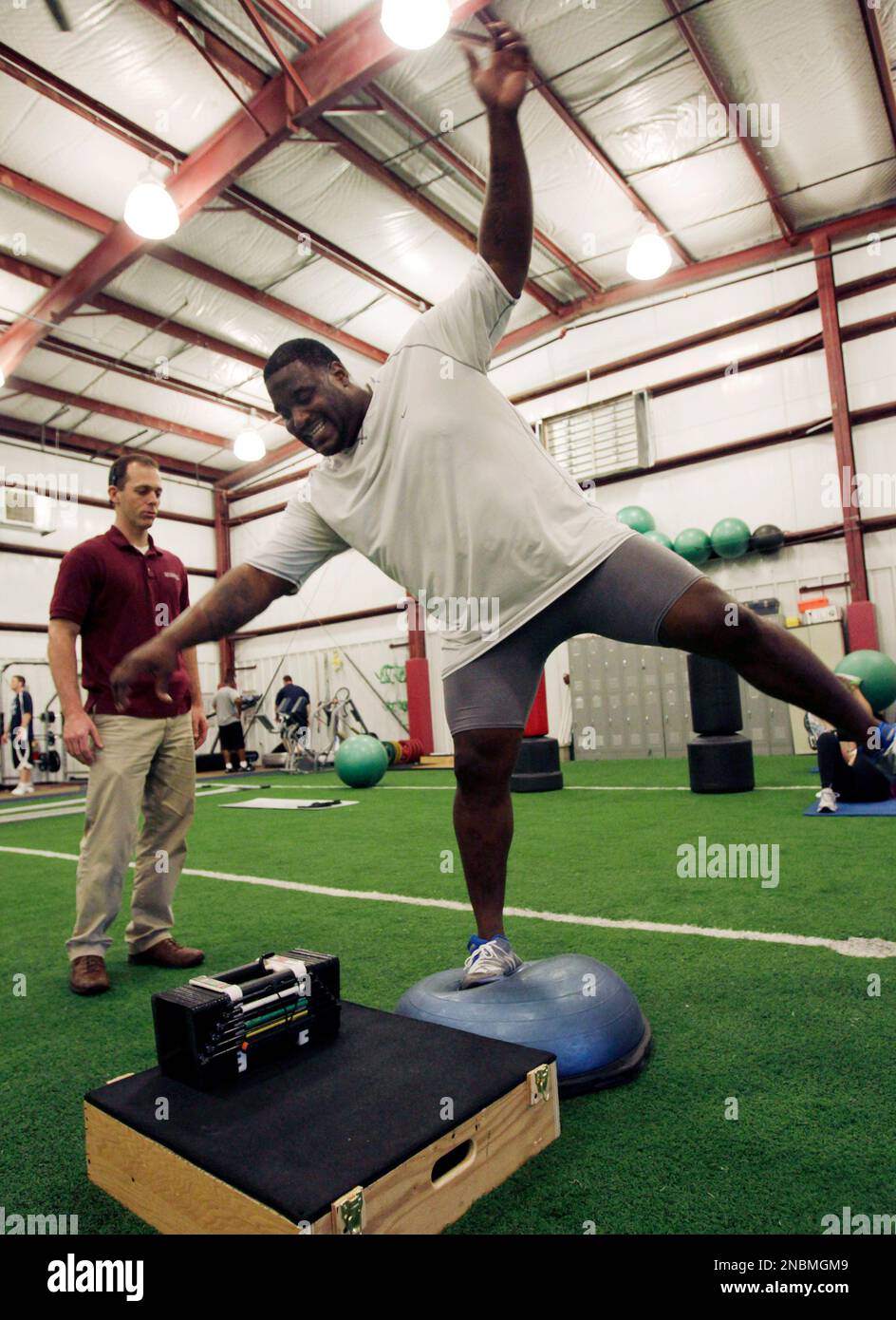 In this photo taken Thursday, June 9, 2011, TEST Sports Club physical therapist Jeff Dillon, left, works with free agent football player Damien Woody at the facility in Martinsville, N.J. Woody is no Nastia Liukin. So when the 320-pound Woody tries to balance, part of his rehab from a ruptured Achilles' tendon, it is, well, a bit awkward. (AP Photo/Mel Evans) Stockfoto