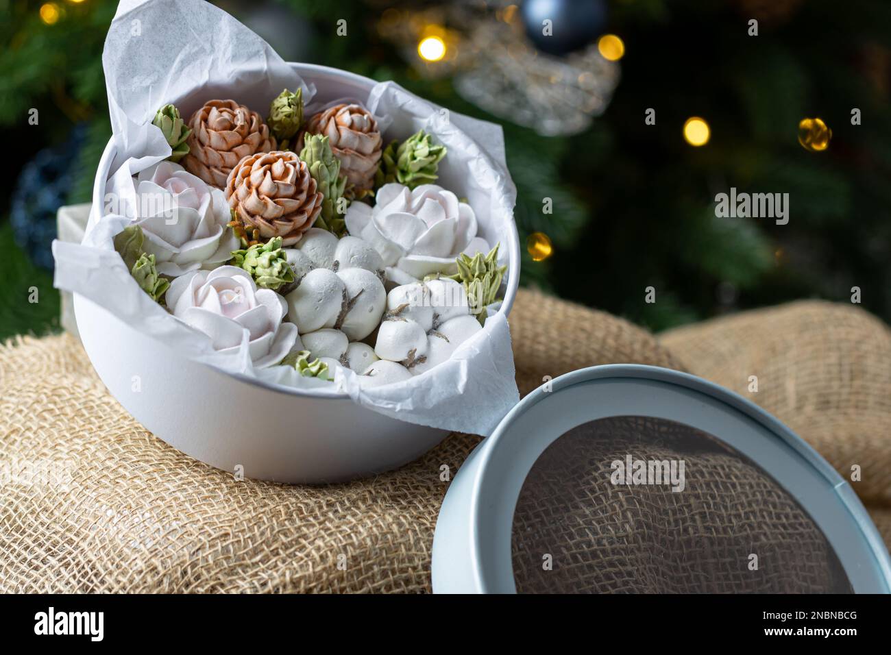 Marshmallow-Blumenstrauß in einer Geschenkbox auf dem Hintergrund eines Weihnachtsbaums, das Konzept einer festlichen Stimmung. Stockfoto
