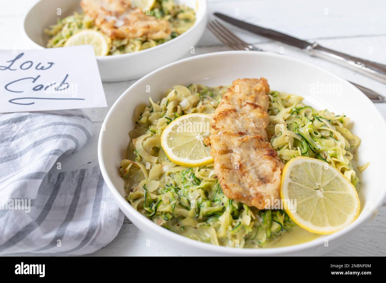 Kohlenhydratarmes Fischgericht mit cremigen Zucchini-Nudeln oder Zoodles auf einem Teller Stockfoto