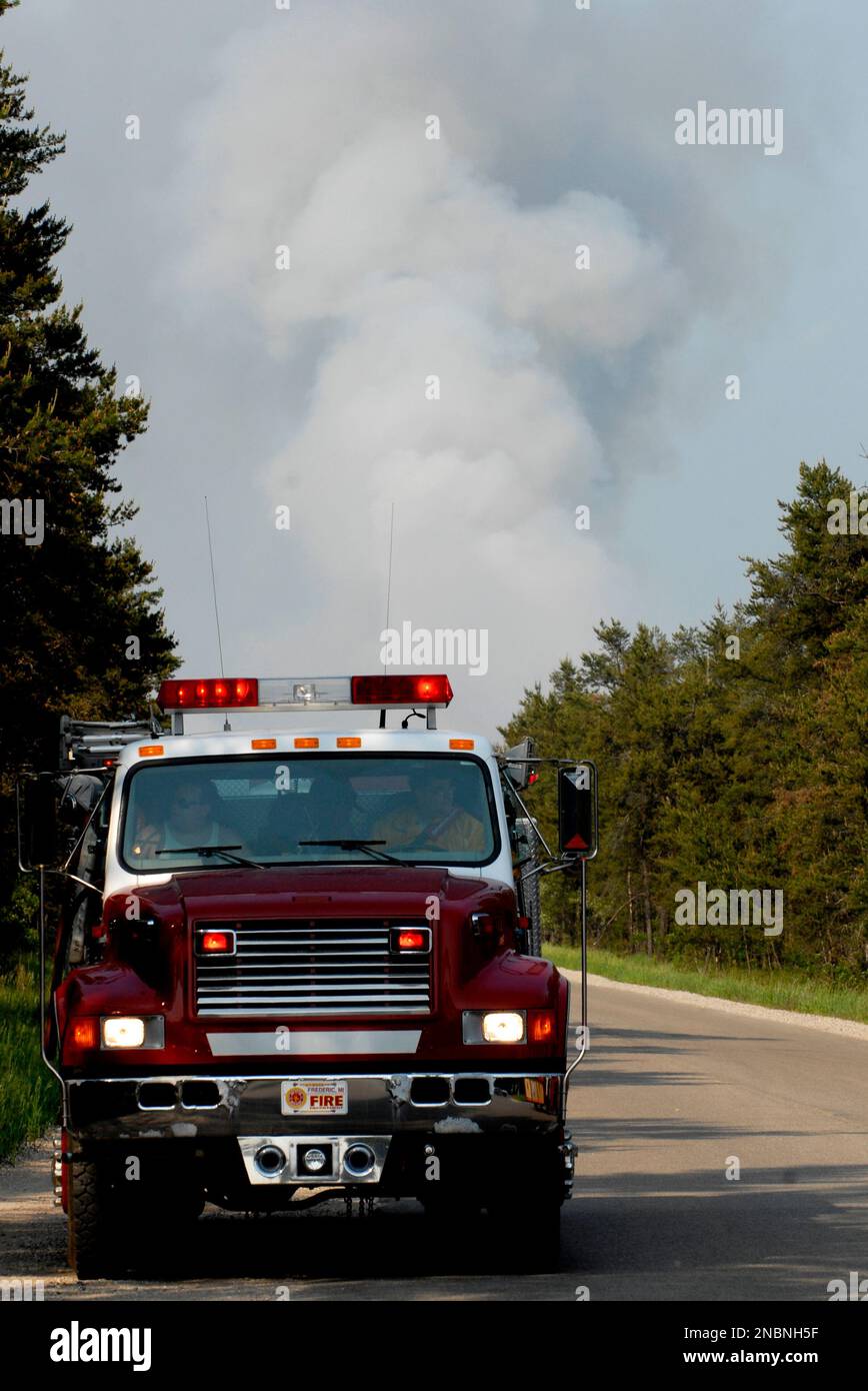 A fire department truck sits along Manistee River Road in Crawford County Tuesday, June 7, 2011 as huge clouds of smoke rise from a forest of jack pine trees to the north. Fire crews had largely contained a blaze Tuesday that burned 750 to 800 acres of northern Michigan woodlands, destroyed or damaged a number of buildings and forced the evacuation of 100 homes, a state spokeswoman said. (AP Photo/John L. Russell) Stockfoto