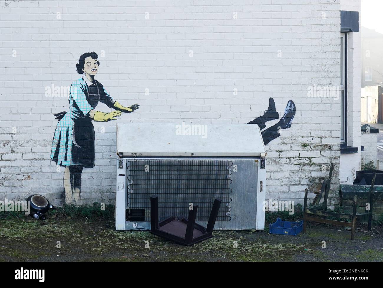 Ein neues Kunstwerk der Straßenkünstlerin Banksy mit dem Titel „Valentinstag Mascara“ an der Seite eines Gebäudes in Margate, Kent. Das Kunstwerk zeigt eine Hausfrau aus den 1950er Jahren, die klassische blaue und gelbe Handschuhe zum Abwaschen trägt, ein geschwollenes Auge und einen fehlenden Zahn hat, wie es scheint, ihren männlichen Partner in eine Gefriertruhe zu schieben. Foto: Dienstag, 14. Februar 2023. Stockfoto