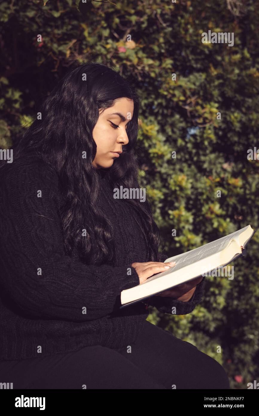 Junge Frau, die im Garten ein Buch liest Stockfoto