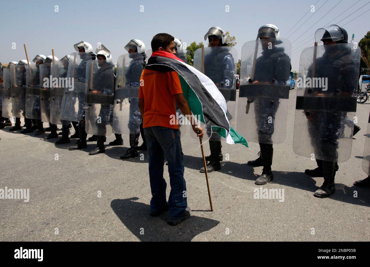 A Palestinian youth, covered with a Palestinian flag, stands next to Hamas riot police near Erez border crossing between Gaza and Israel on Sunday, June 5, 2011. Hamas riot police prevented Palestinian protesters from marching to the border with Israel on the anniversary of the Arab defeat in the 1967 Mideast war. (AP Photo/Hatem Moussa) Stockfoto