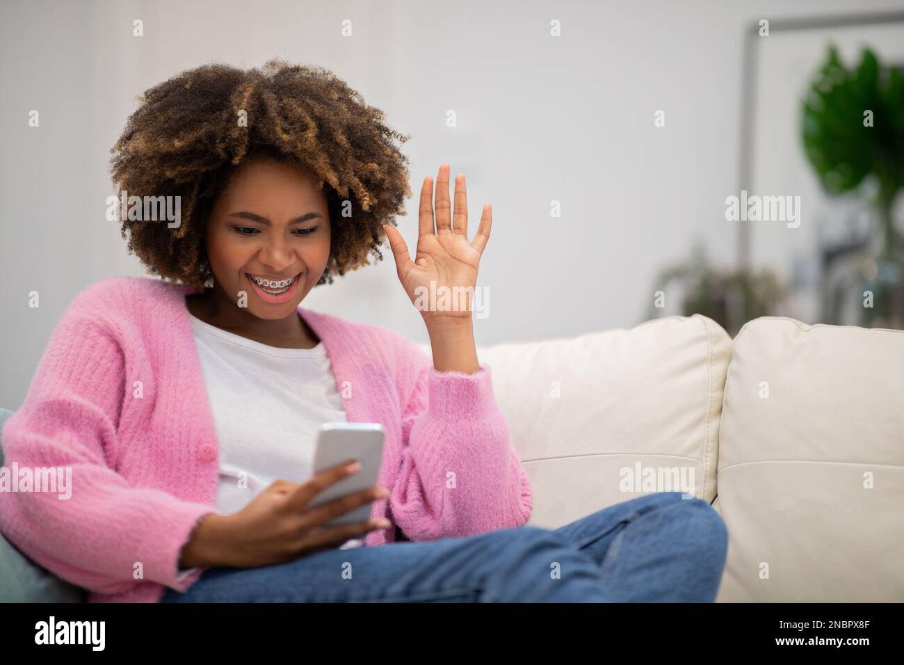 Glückliche, wunderschöne junge afrikanerin, die zu Hause Videoanrufe führt Stockfoto