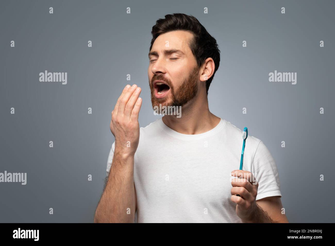 Ein Mann mittleren Alters, der die Hand nahe am Mund hält und die Atemfristigkeit prüft, besorgt über schlechte Mundhygiene Stockfoto