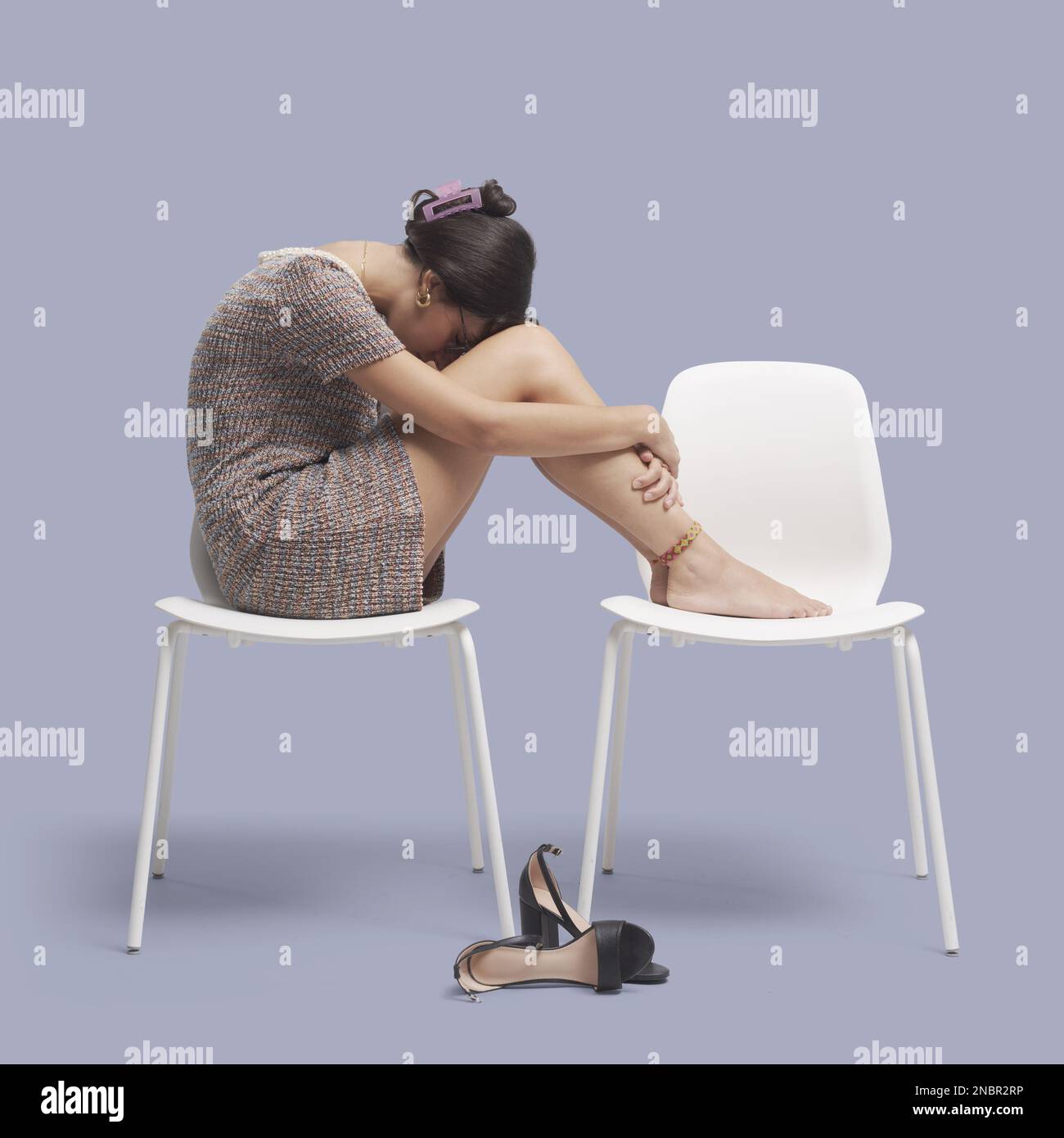 Depressive müde Geschäftsfrau, die auf einem Stuhl sitzt und sich mit den Füßen nach oben ausruht Stockfoto
