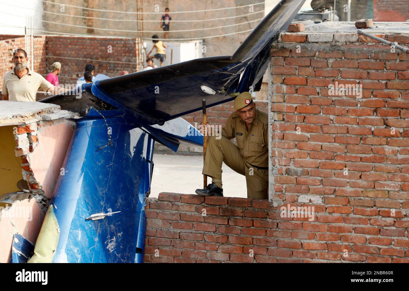 A policeman stands guard near the remnants of a small plane that crashed in Faridabad, near New Delhi, India, Thursday, May 26, 2011. The chartered plane being used as an air ambulance to ferry a patient to a New Delhi hospital crashed Wednesday into a residential neighborhood on the outskirts of the Indian capital, killing 10 people, government officials said. (AP Photo/Saurabh Das) Stockfoto