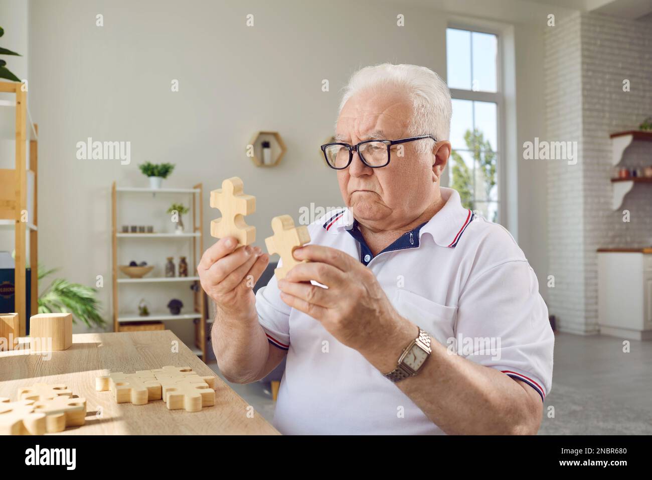 Fokussierter Senior-Mann, der zu Hause Puzzle spielt Stockfoto