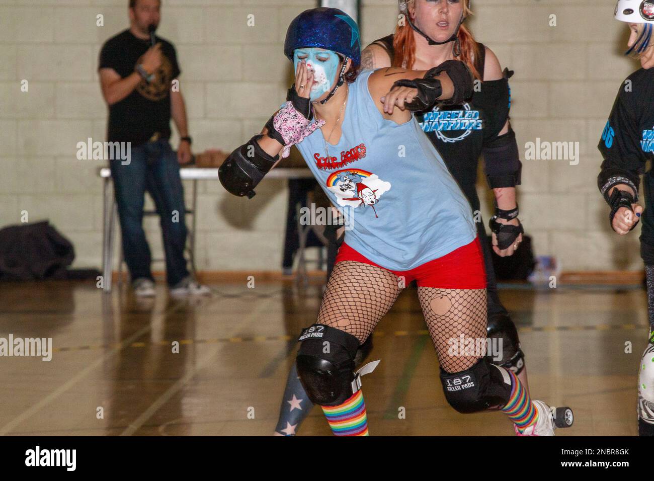 Ein Roller-Derby-Jammer fährt los und hält ihr Gesicht fest, wo sie hoffentlich versehentlich getroffen wurde Stockfoto