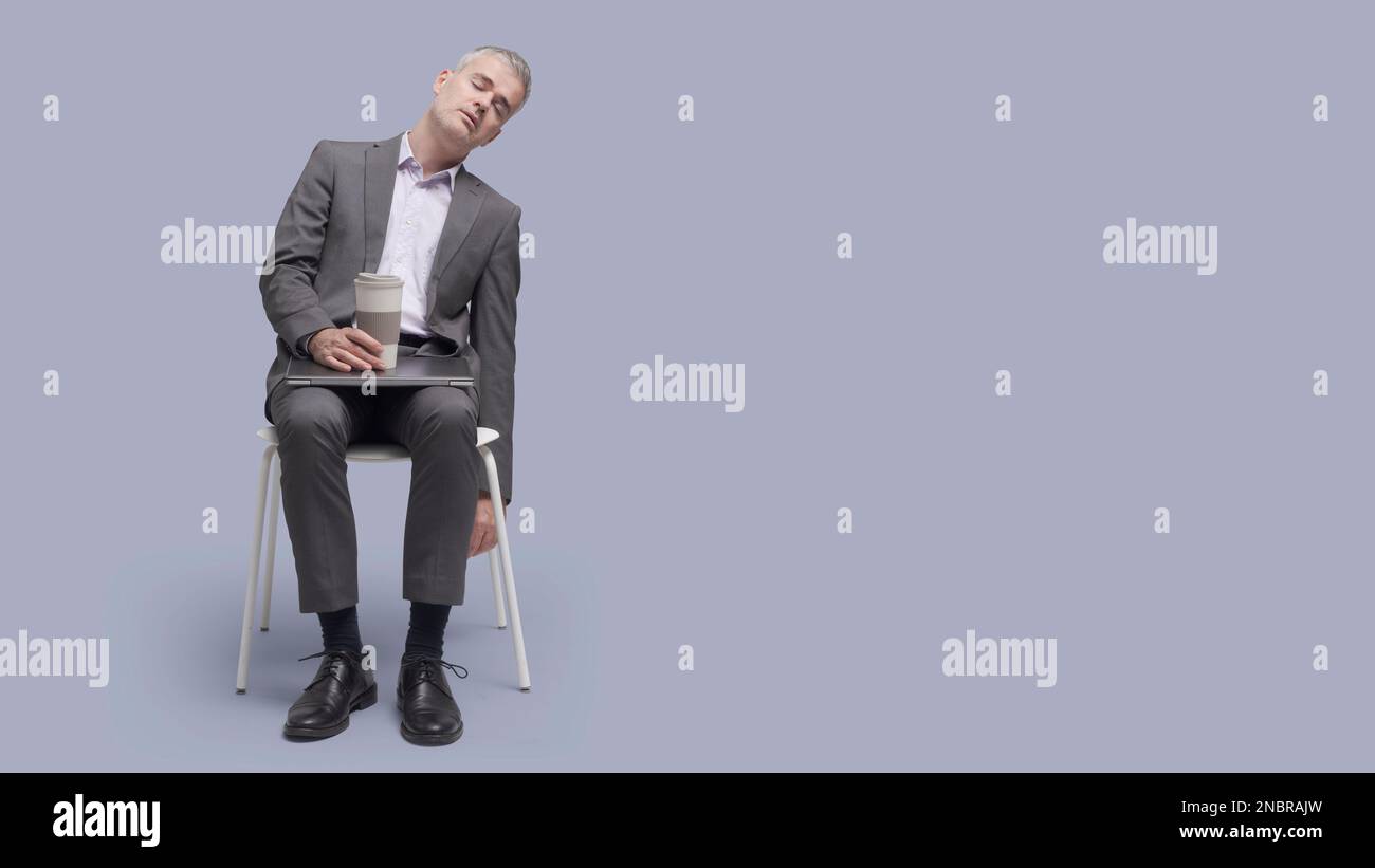 Fauler, müde Geschäftsmann sitzt auf einem Stuhl und schläft ein Stockfoto