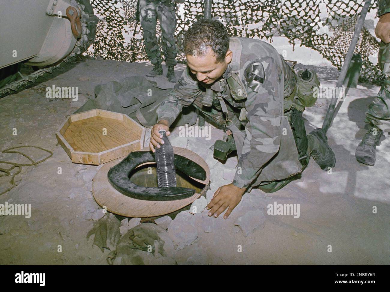 U.S. Army Sgt. William Carter, of Fayetteville, N.C., retrieves a bottle of chilled water from a makeshift cooler that uses a toilet seat as a cover, in the Saudi desert, Oct. 24, 1990. Members of the 6th Platoon of the 92nd Field Artillery, 1st Cavalry Division, of Ft. Hood, Texas, disguised the cooler as a latrine to prevent raids on their stash of cold water. (AP Photo/Dave Martin) Stockfoto