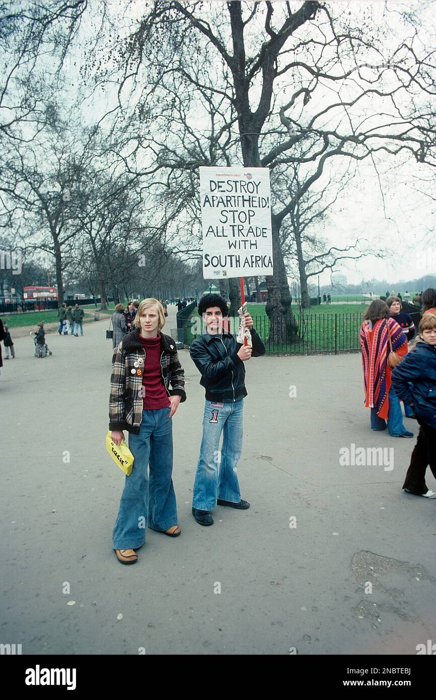 London 1977. Ein junger Mann, der ein handgeschriebenes Schild mit dem Text "Zerstöre Apartheid" hält! Stoppt den Handel mit Südafrika. Die beiden Männer tragen die typischen weithalsigen Jeans, die aus den 1970er Jahren stammen. Kristoffersson Ref. DV2 Stockfoto