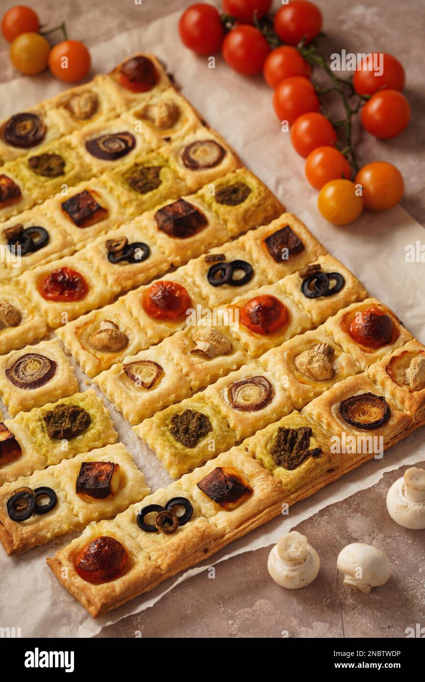 Blätterteiggebäck mit Kirschtomaten, Pilzen, Oliven, Fetakäse und Zwiebeln. Stockfoto