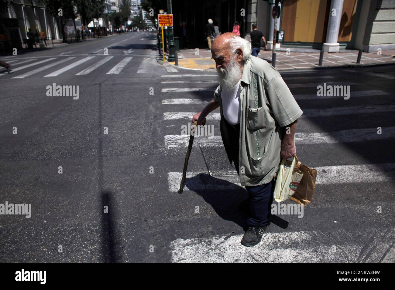 An elderly man walks through central Athens as streets are deserted following violent protests on Wednesday, May 11, 2011. Clashes broke out after thousands of protesters joined the rally during a general strike called in opposition to harsh austerity measures intended to keep the debt-ridden country solvent. (AP Photo/ Kostas Tsironis) Stockfoto