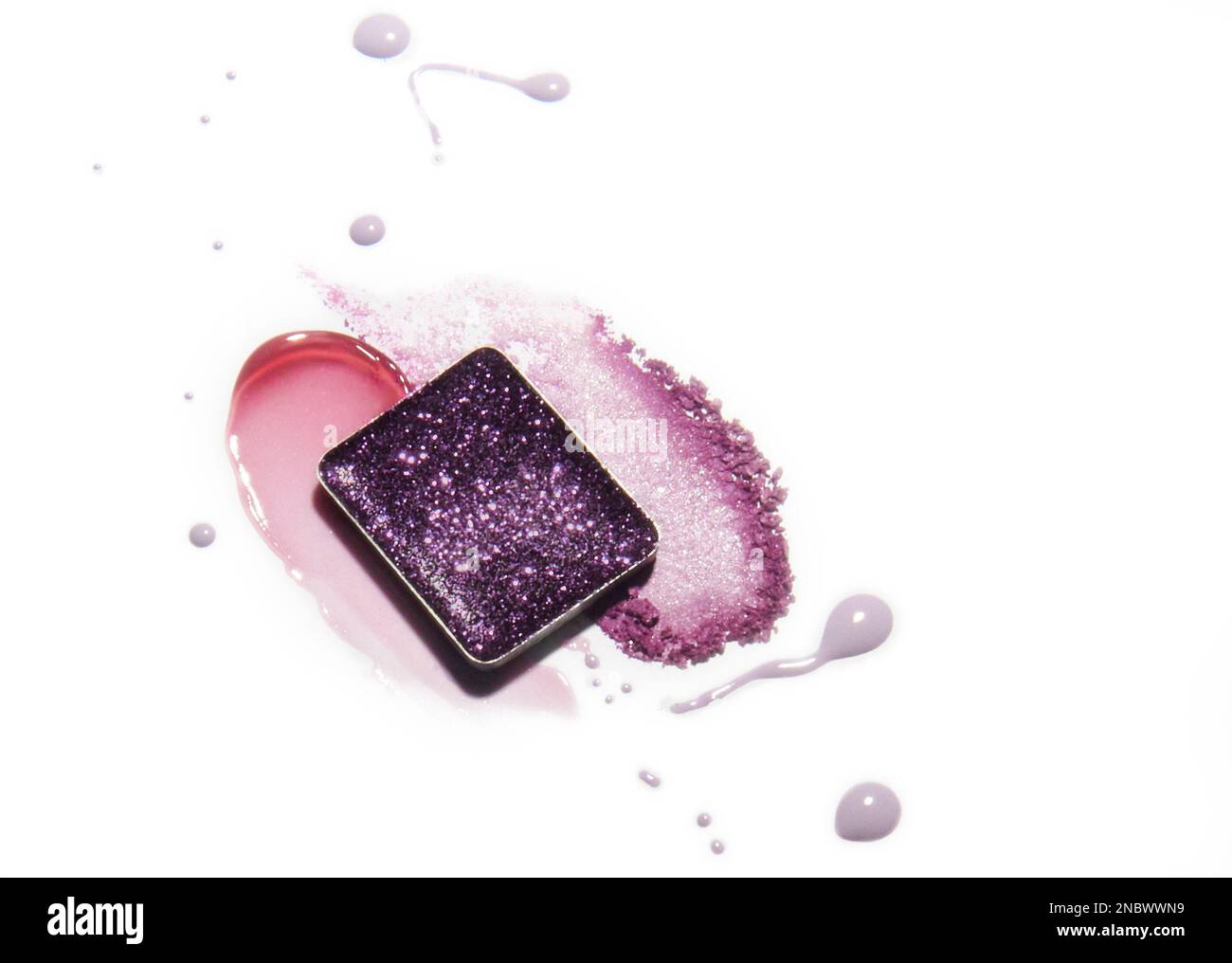 Make-up-Farbfelder: Dunkelvioletter Lidschatten, pinkfarbene und lila Lippenglänzend und hellviolette Spritzer auf weißem Hintergrund. Stockfoto